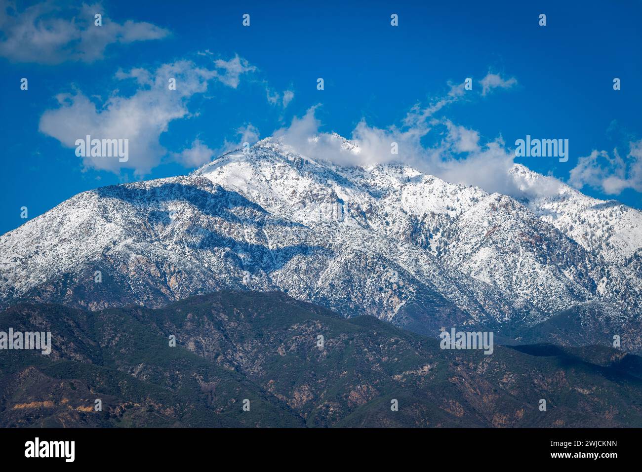 Première neige sur Ontario Peak dans la forêt nationale d'Angeles avec des nuages dispersés projetant des ombres sur le flanc de la montagne. Banque D'Images