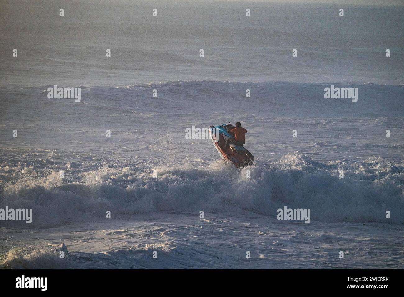 Jet ski saut au-dessus d'une vague dans l'océan Atlantique orageux, Nazare, Portugal Banque D'Images