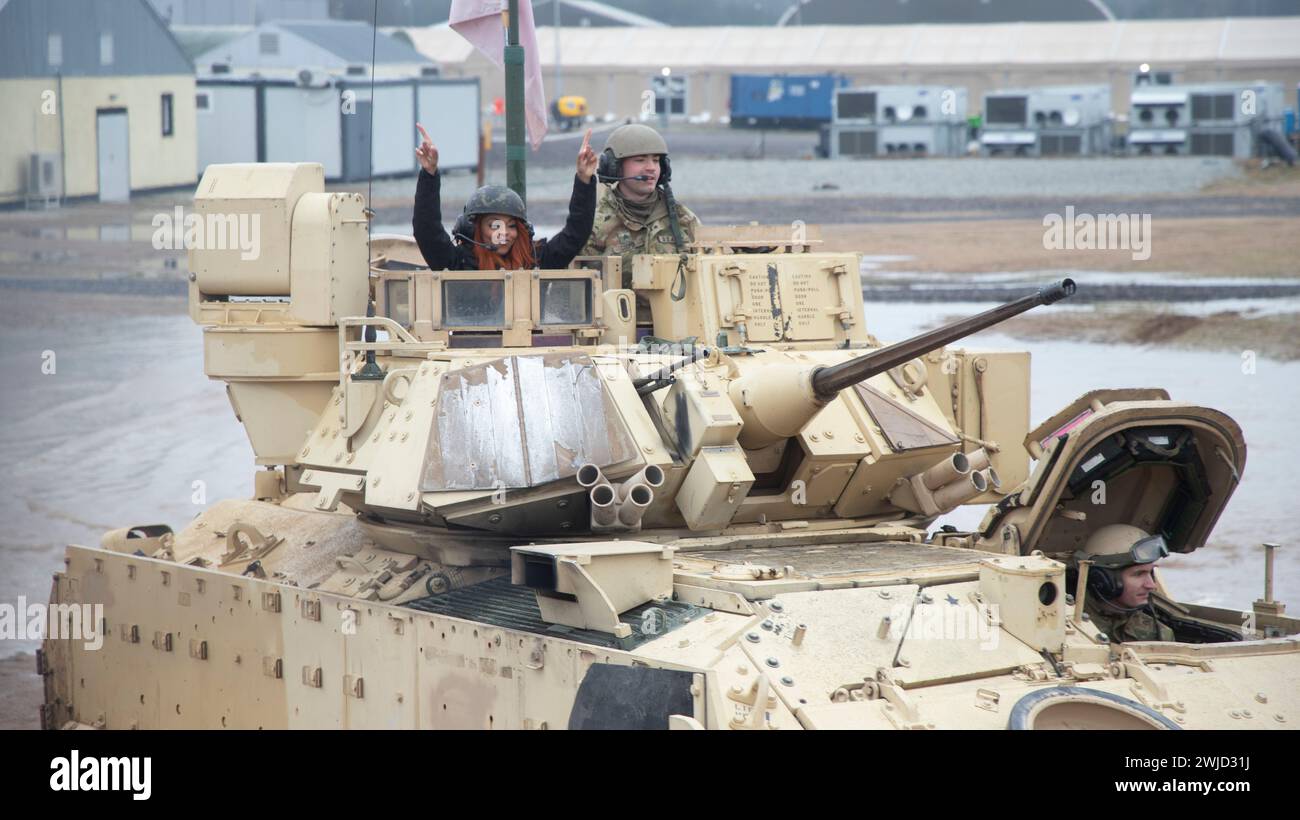 Drawsko Pomorskie, Pologne. 10 février 2024. Bre, cheerleader des commandants de Washington, lève les bras alors qu'elle fait un tour dans un char de combat principal M1A2 Abrams de l'armée américaine avec la 1re division blindée au Drawsko combat Training Center, le 10 février 2024 à Drawsko Pomorskie, dans la voïvodie de Poméranie occidentale, Pologne. La National Football League s'est associée à l'Armed Forces Entertainment dans le cadre de Pro Blitz 2024. Crédit : SPC. Trevares Johnson/US Army/Alamy Live News Banque D'Images