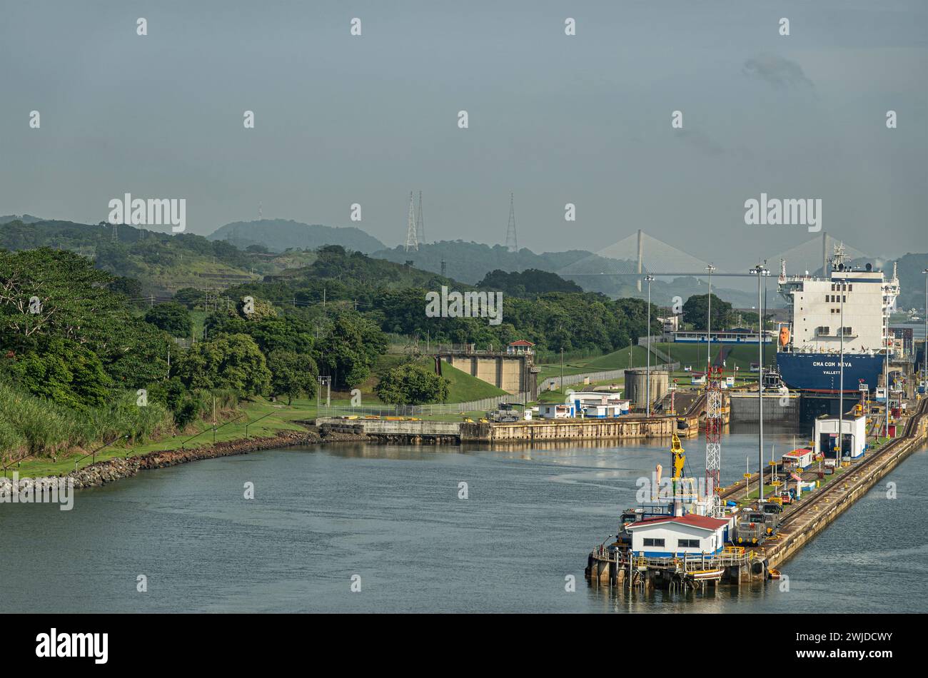 Canal de Panama, Panama - 24 juillet 2023 : chambres de gauche de Miraflores écluses pour aller au nord sous le ciel bleu clair. Navire porte-conteneurs CMA CGM. Pont centenaire sur Banque D'Images