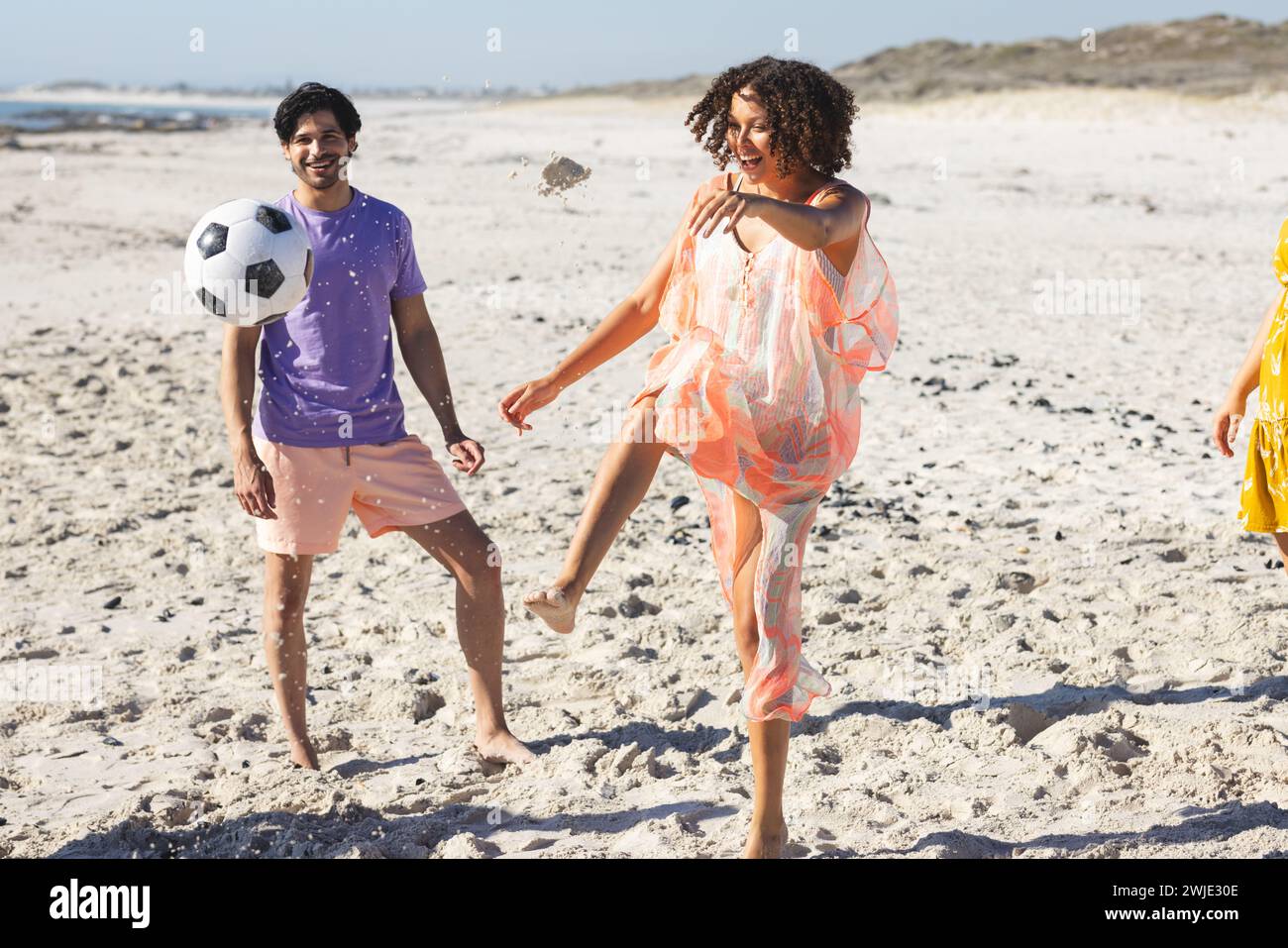 Jeune couple biracial aime un match de football sur la plage Banque D'Images