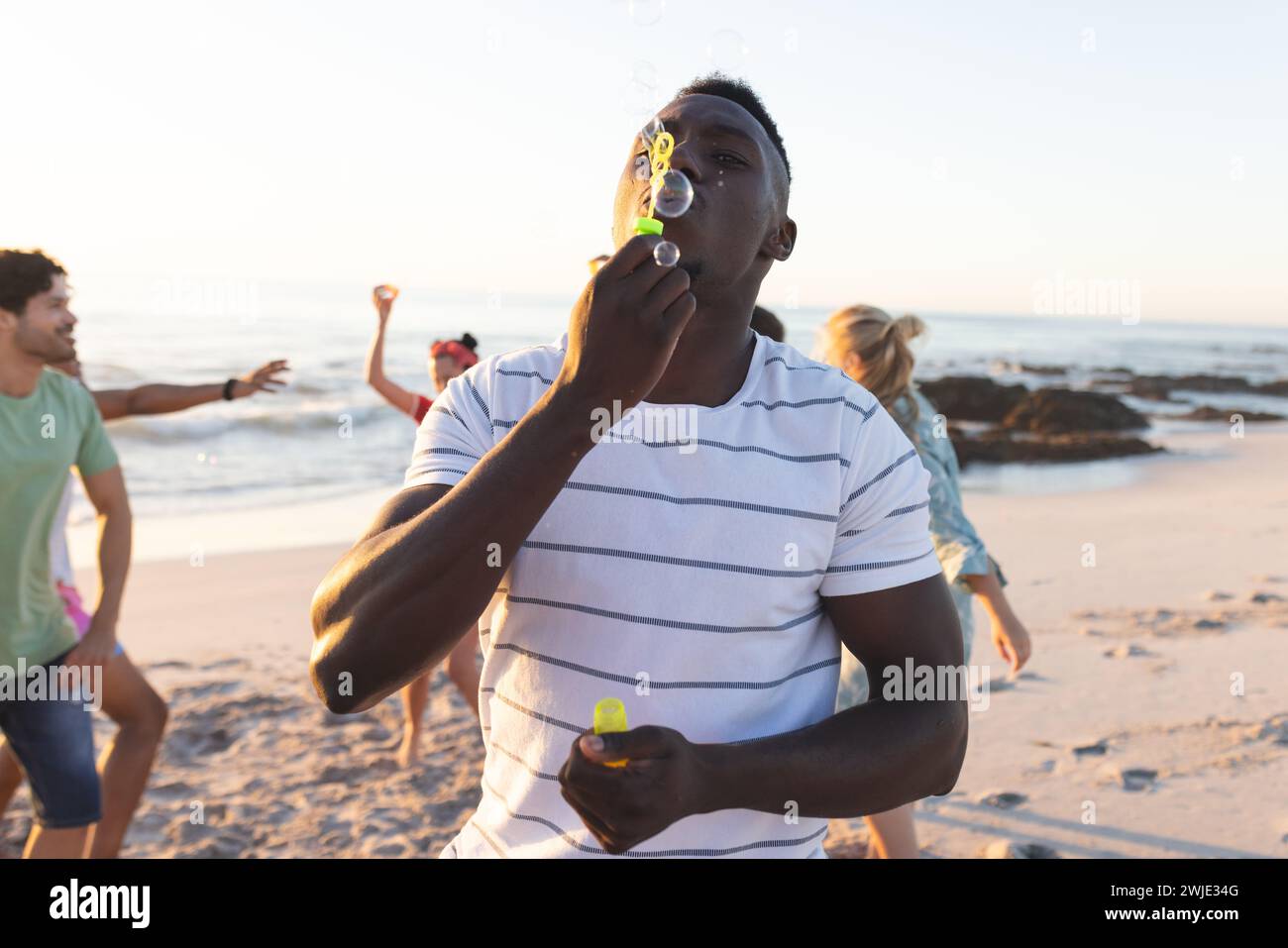 Un jeune homme afro-américain souffle des bulles sur la plage Banque D'Images