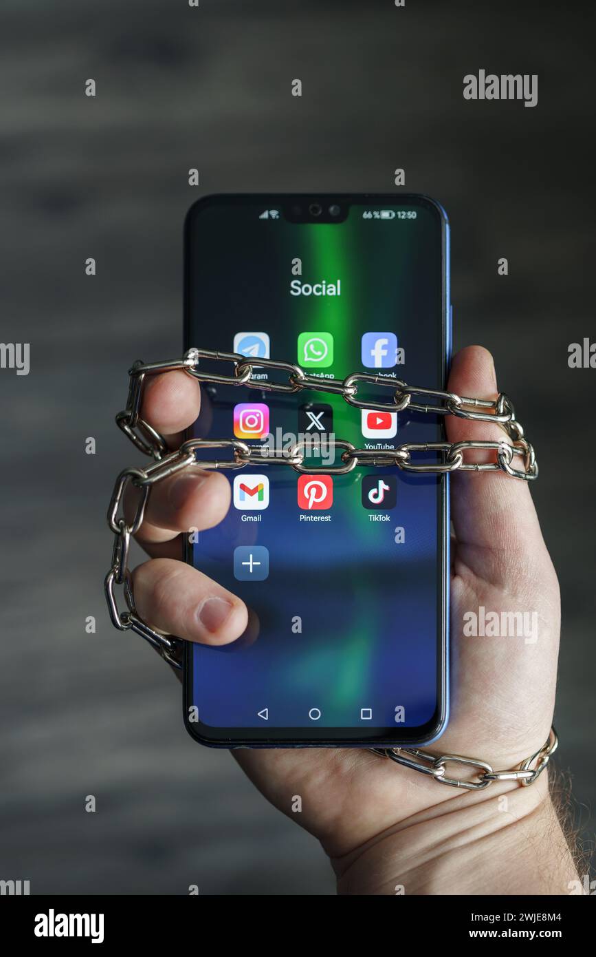 Ouzbékistan, Tachkent - 27 janvier 2024 : chaîne à portée de main avec téléphone mobile avec icônes de réseau social. Concept de limitation du temps sur les réseaux sociaux, addic Banque D'Images