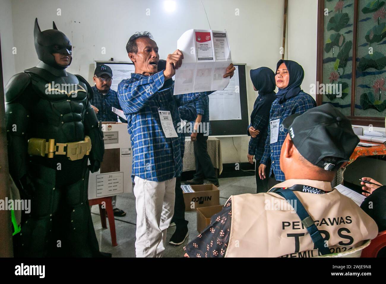 Un fonctionnaire électoral portant le costume de Batman travaille pendant la présidence indonésienne dans un bureau de vote à Bogor, Indonésie, le 14 février 2024 Banque D'Images