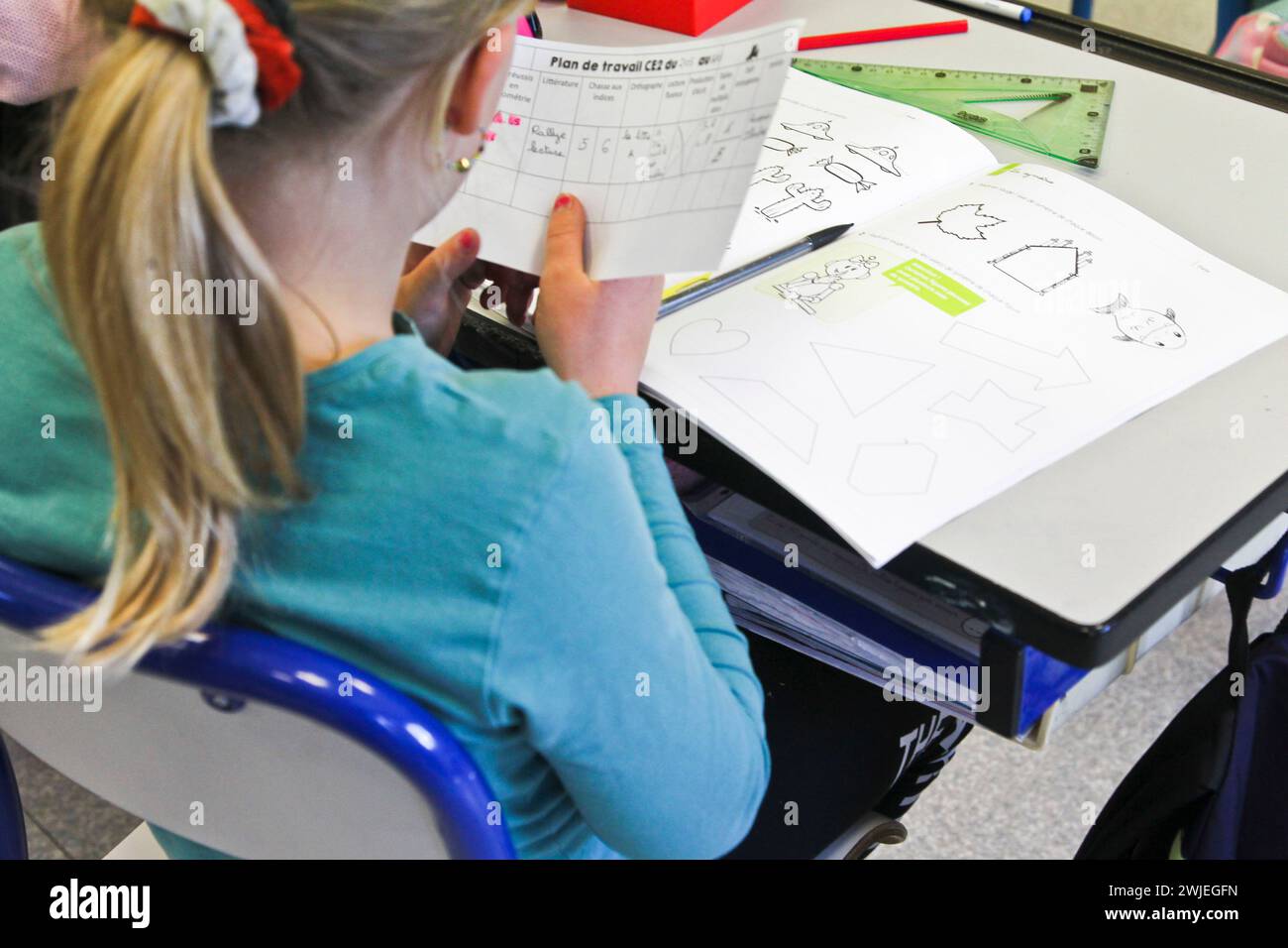 Arvieux, département des Hautes-Alpes (Alpes françaises), Queyras : classe primaire. Écolière assise à son bureau, écrivant dans son cahier d'exercices Banque D'Images