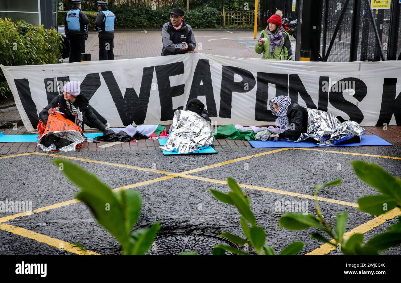 Les manifestants s'enveloppent dans des couvertures thermiques contre le froid alors qu'ils sont allongés sur le sol dans la chaussée devant Elbit Systems devant une grande bannière disant « UK Weapons Kill ». Les partisans de Palestine action utilisent des verrous pour bloquer le seul accès des véhicules à la société de défense israélienne, l'entreprise Elbit Systems à Aztec West, Bristol. Ils soutiennent que les armes fabriquées par Elbit au Royaume-Uni sont utilisées par les Forces de défense israéliennes contre les Palestiniens à Gaza et ailleurs. Les bombardements israéliens à Gaza ont tué plus de 30 000 Palestiniens depuis octobre 2023. Palestine action sont déterminés à implacable Banque D'Images