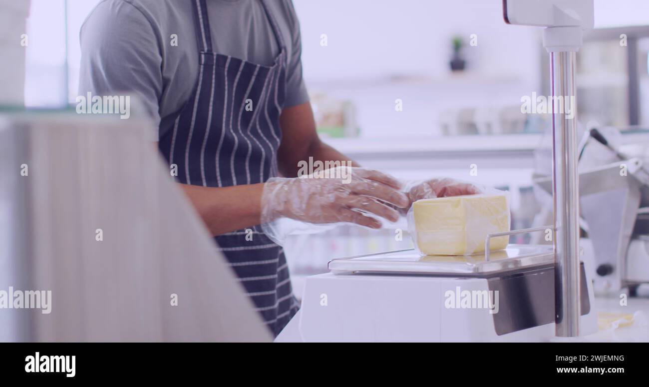 L'homme afro-américain tranche du fromage dans une cuisine lumineuse Banque D'Images