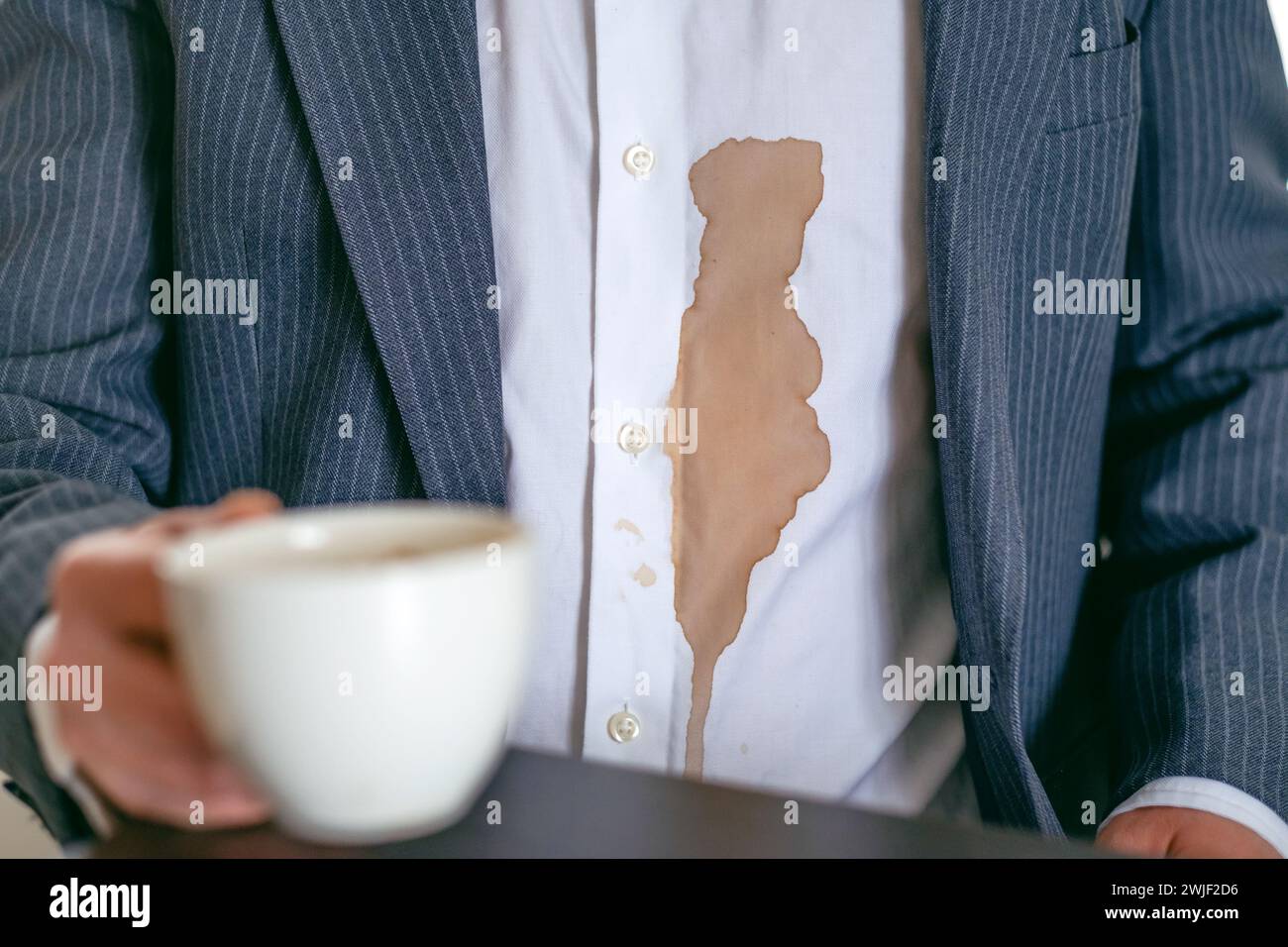 Un homme méconnaissable renversa du café ou du thé sur une chemise blanche. concept de coloration de la vie quotidienne. Banque D'Images