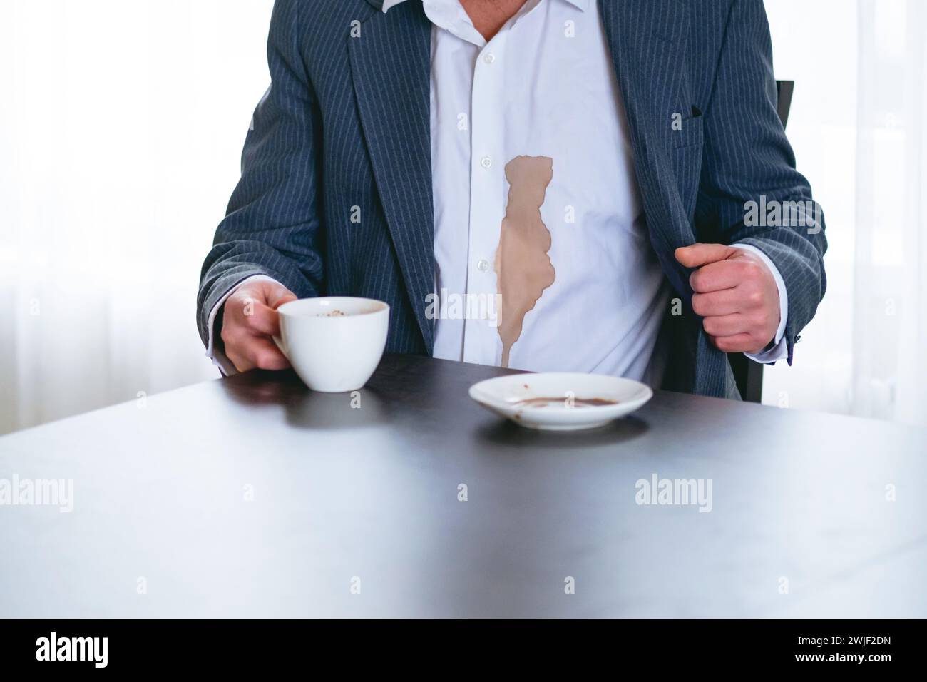 Un homme méconnaissable renversa du café ou du thé sur une chemise blanche. concept de coloration de la vie quotidienne. Banque D'Images