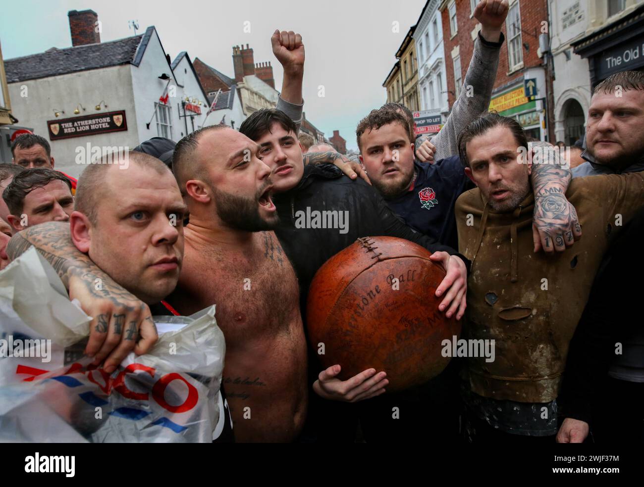 Atherstone, Royaume-Uni. 13 février 2024. Les joueurs chantent le nom du vainqueur 2017 Danny Murphyís qui est mort la semaine dernière alors que le jeu s’arrête pour un silence minuteís. Les joueurs se rassemblent pour jouer au jeu de balle Atherstone. Le jeu de 2024 est le 824ème et il remonte à 1199. Il voit des joueurs lutter dans la rue pour la possession d'un ballon surdimensionné. Celui qui tient le ballon après deux heures gagne. Le match honore un match joué entre le Leicestershire et le Warwickshire en 1199, lorsque les équipes ont utilisé un sac d'or comme balle. (Photo de Martin Pope/SOPA images/SIPA USA) crédit : SIPA USA/Alamy Live News Banque D'Images