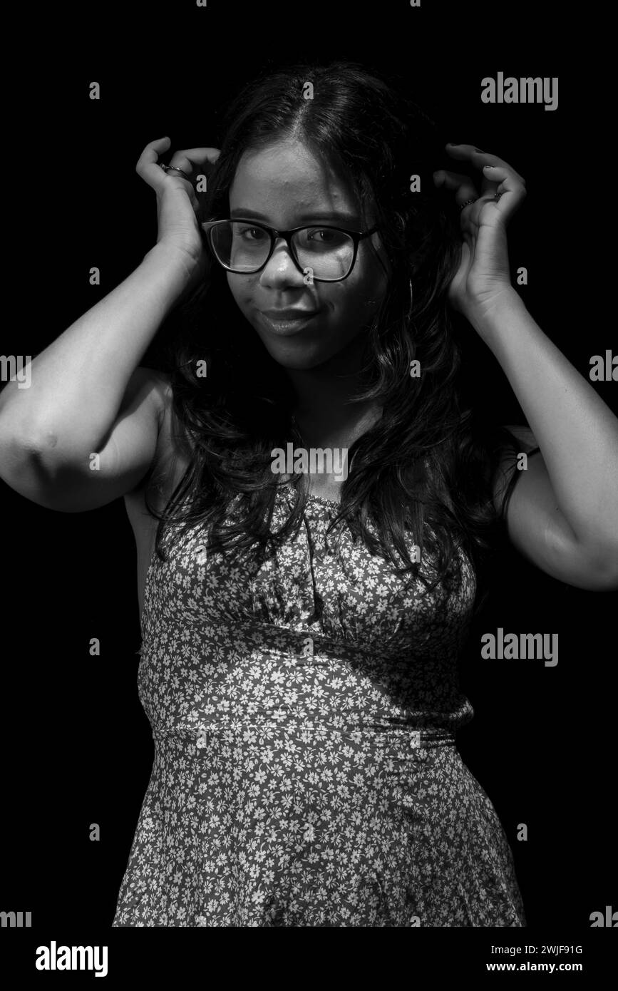 Salvador, bahia, Brésil - 09 décembre 2023 : portrait en noir et blanc d'une jeune femme aux cheveux raides portant des lunettes posant pour la photo. Banque D'Images