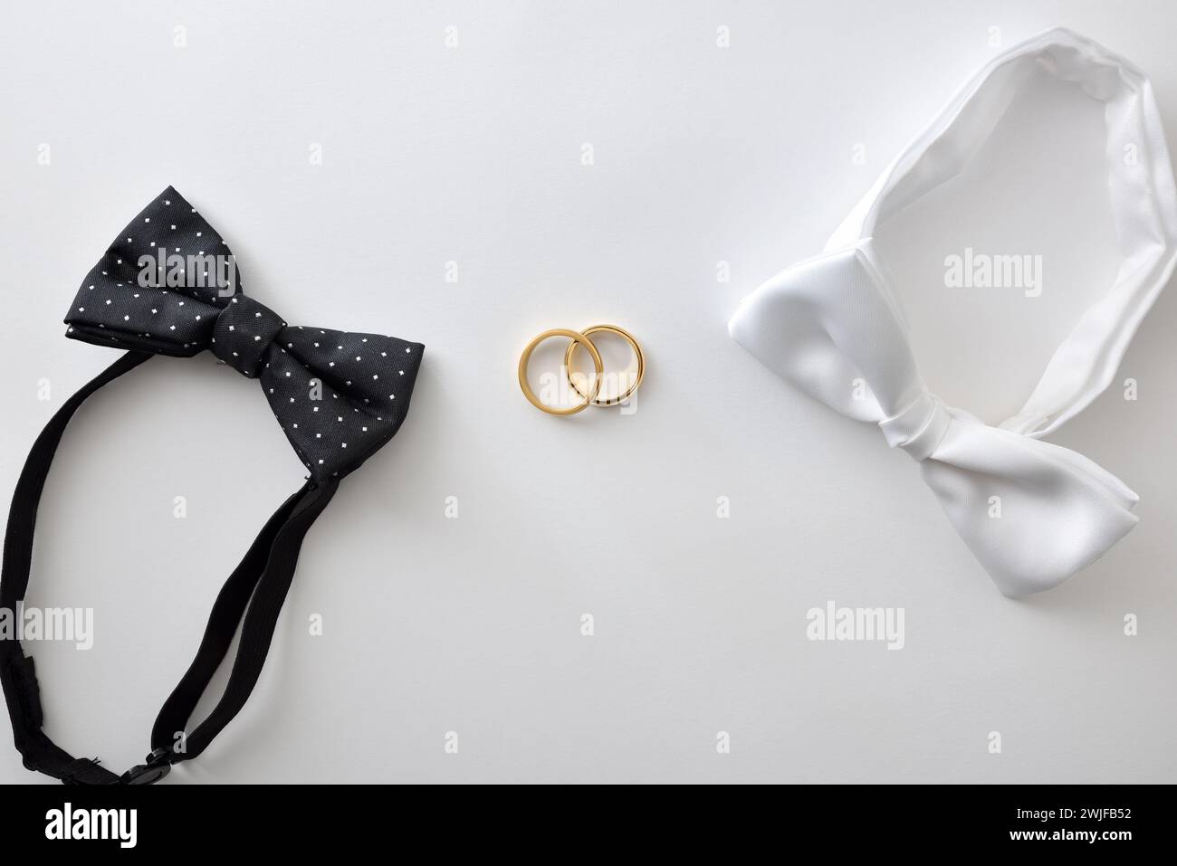 Concept de mariage gay avec noeud papillon noir avec pois et blanc sur les côtés des anneaux de mariage au milieu. Vue de dessus. Banque D'Images