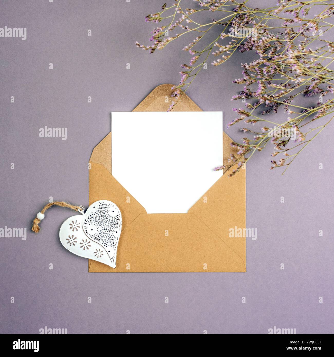 Enveloppe avec carte vierge, coeur de jouet vintage et fleurs sur fond gris. Saint-Valentin, concept de la journée des femmes, vue de dessus, pose à plat, maquette. Banque D'Images