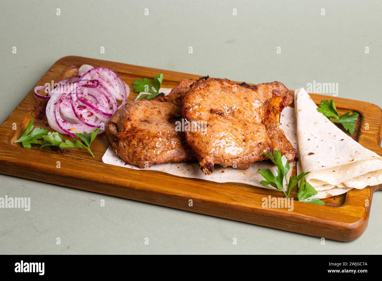 Brochettes de porc grillées avec pita et herbes, parfaitement cuites et carbonisées. Délicieux, juteux, servi sur planche de bois sous un éclairage chaleureux. Banque D'Images
