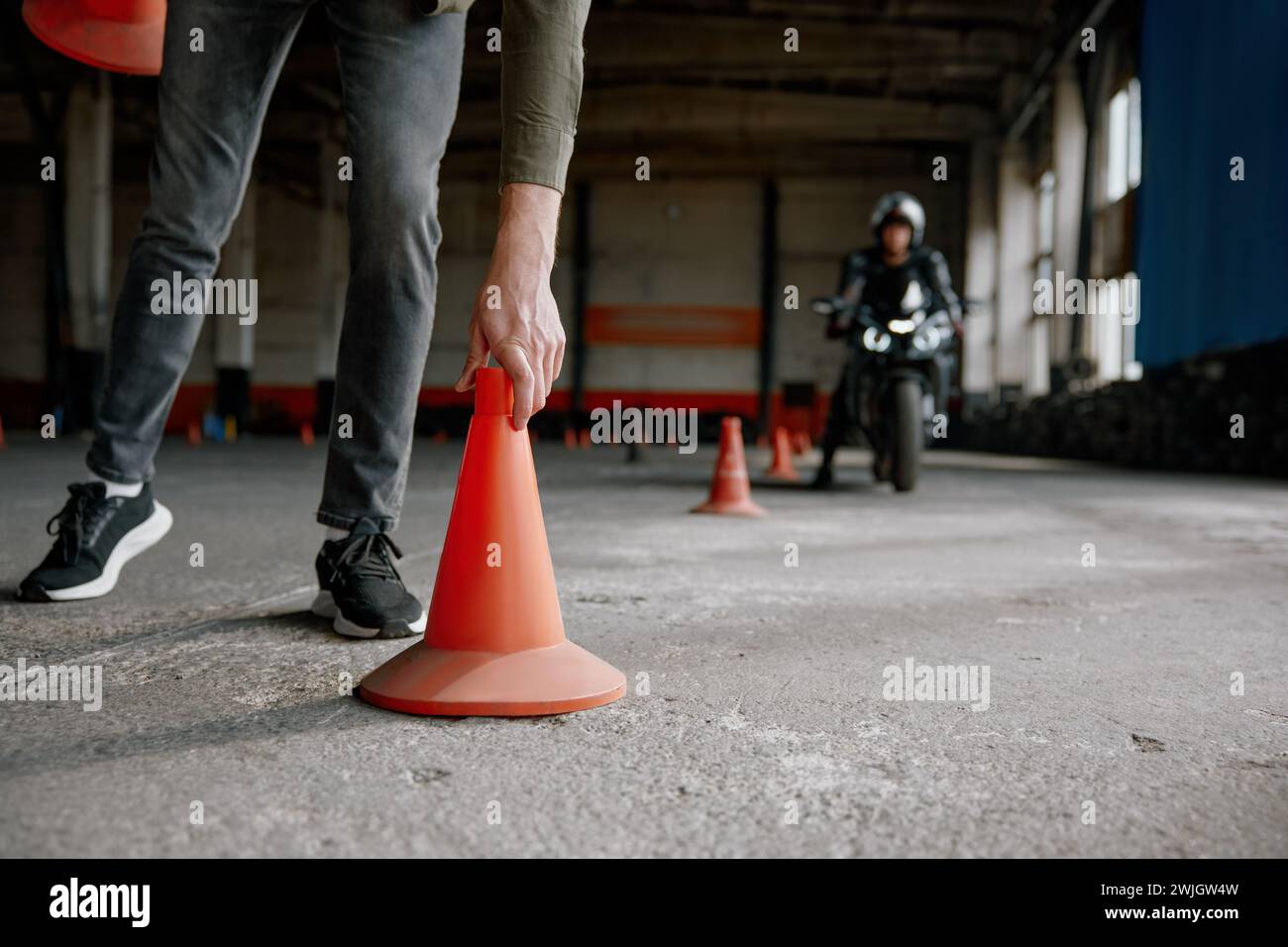 Leçon d'école de conduite de moto avec instructeur mettant le cône sur la piste Banque D'Images