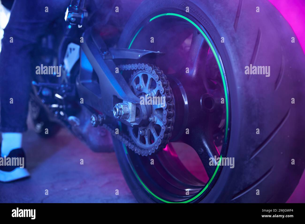 Vue arrière des roues de moto sport dans la lumière néon et la fumée Banque D'Images