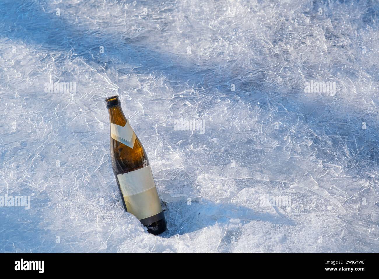 une bouteille de bière dans la glace sur la rive de la rivière Banque D'Images