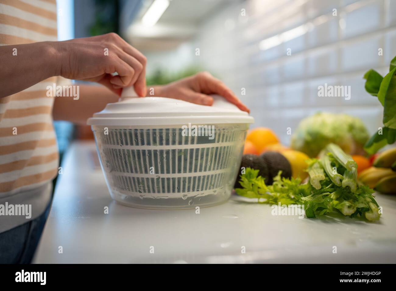 Les mains sèchent les épinards verts, le persil et le céleri dans la centrifugeuse sèche-mains. Ingrédients frais pour la salade Banque D'Images