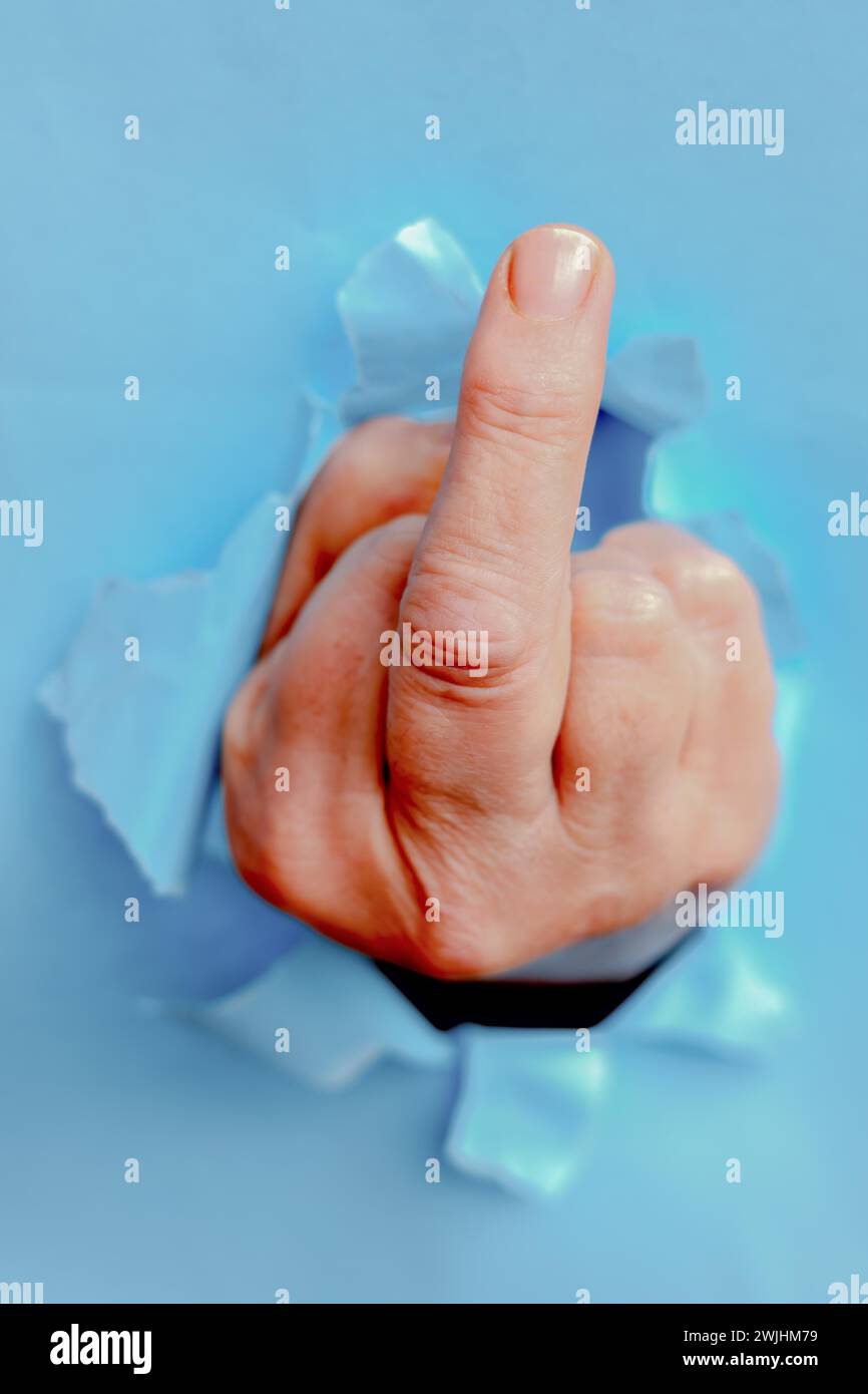 Main de femme avec le majeur levé émergeant d'un carton déchiré Banque D'Images