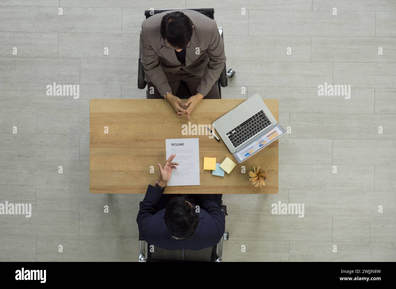 Le jeune candidat asiatique a présenté son curriculum vitae au gestionnaire des ressources humaines en costume lors de l'entrevue. Vue de dessus Banque D'Images