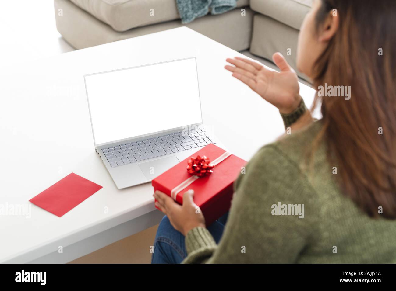 Jeune femme biraciale célèbre une fête d'anniversaire virtuelle à la maison sur un appel vidéo Banque D'Images