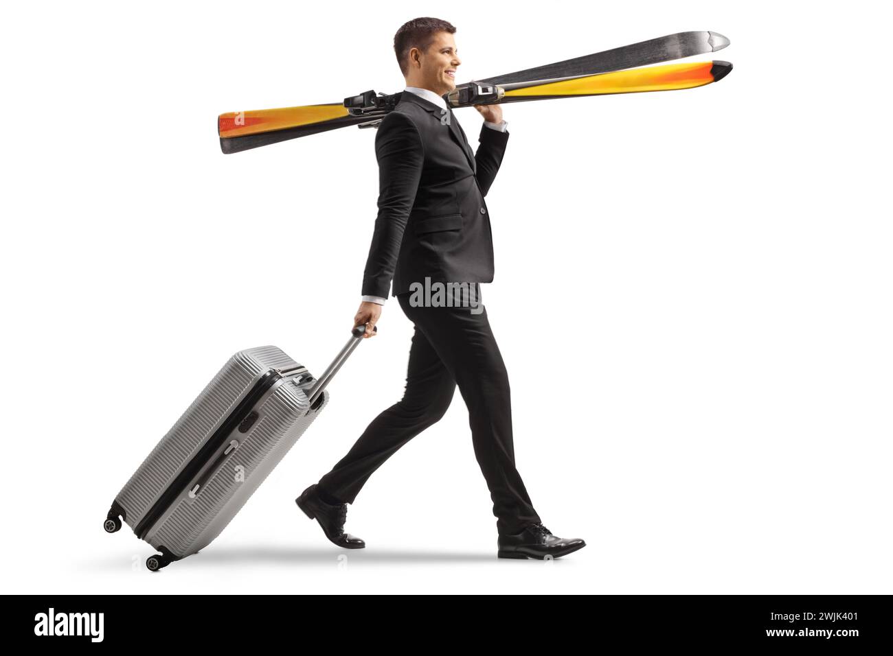 Plan de profil pleine longueur d'un homme d'affaires portant des skiis et tirant une valise isolé sur un fond blanc Banque D'Images