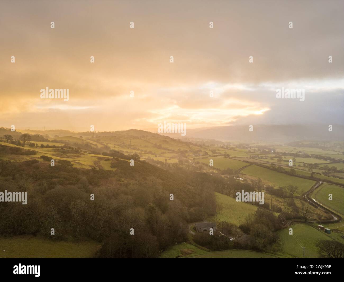 Lever du soleil sur les collines et les terres agricoles dans le Denbighshire, avec la lumière tôt le matin se brisant à travers les nuages au-dessus du paysage rural gallois. Banque D'Images