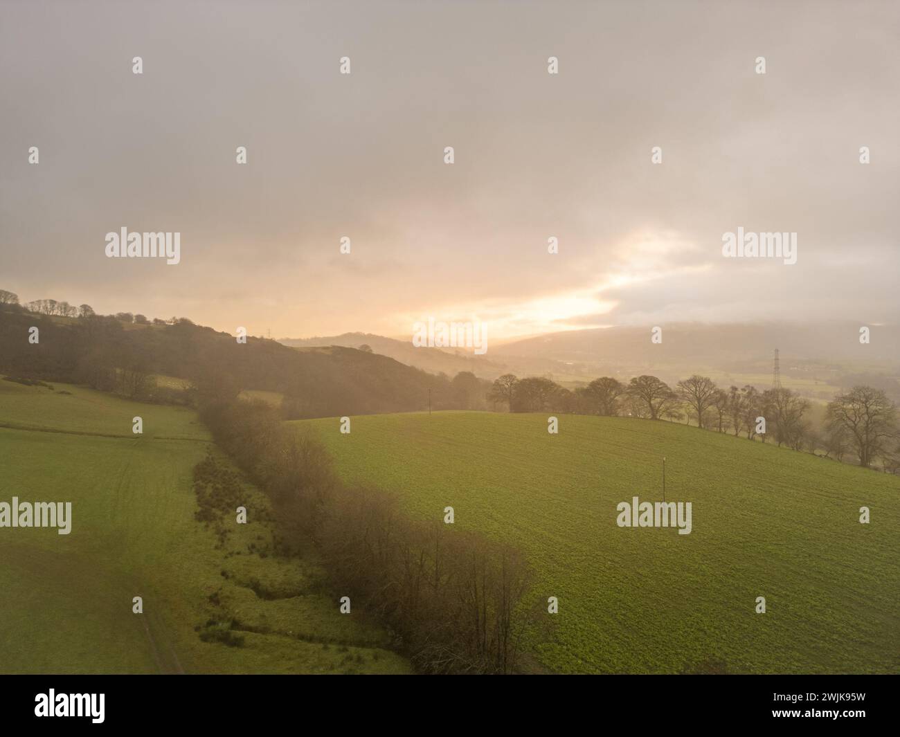 Lever du soleil sur les collines et les terres agricoles dans le Denbighshire, avec la lumière tôt le matin se brisant à travers les nuages au-dessus du paysage rural gallois. Banque D'Images