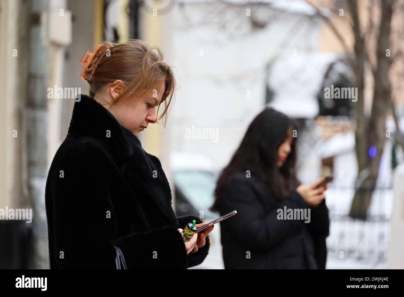Femmes debout avec des smartphones dans les mains sur la rue de la ville d'hiver Banque D'Images