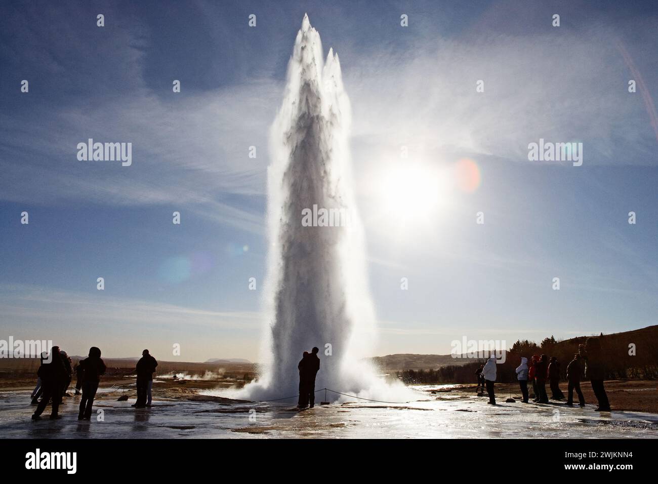 Un geyser dans un champ avec des gens debout autour Banque D'Images