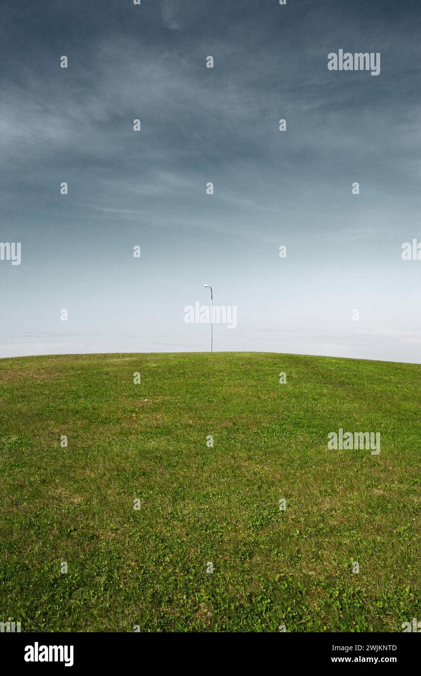 Un champ d'herbe avec un poteau au loin Banque D'Images