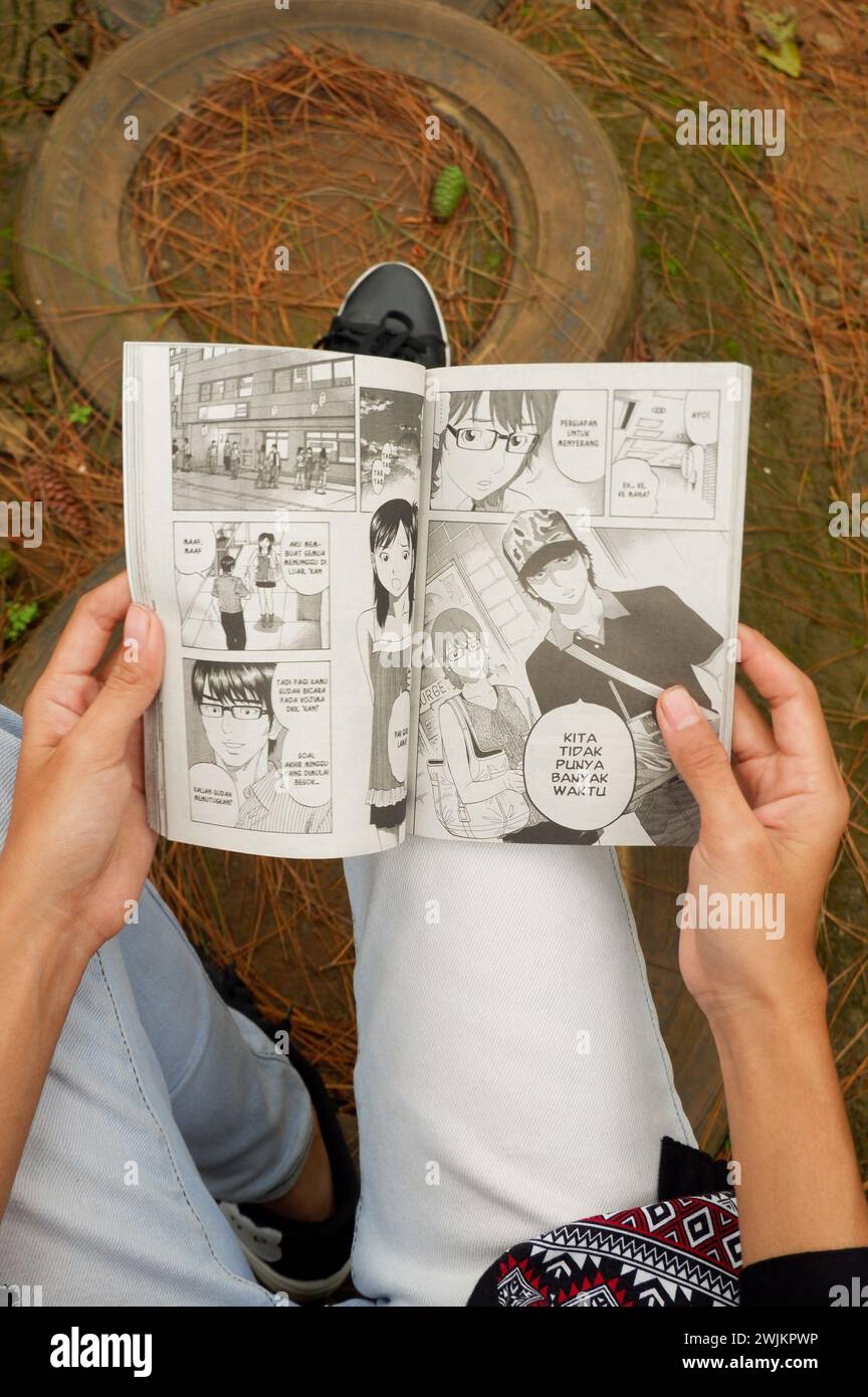 Photo d'une femme asiatique lisant une bande dessinée en indonésien Banque D'Images