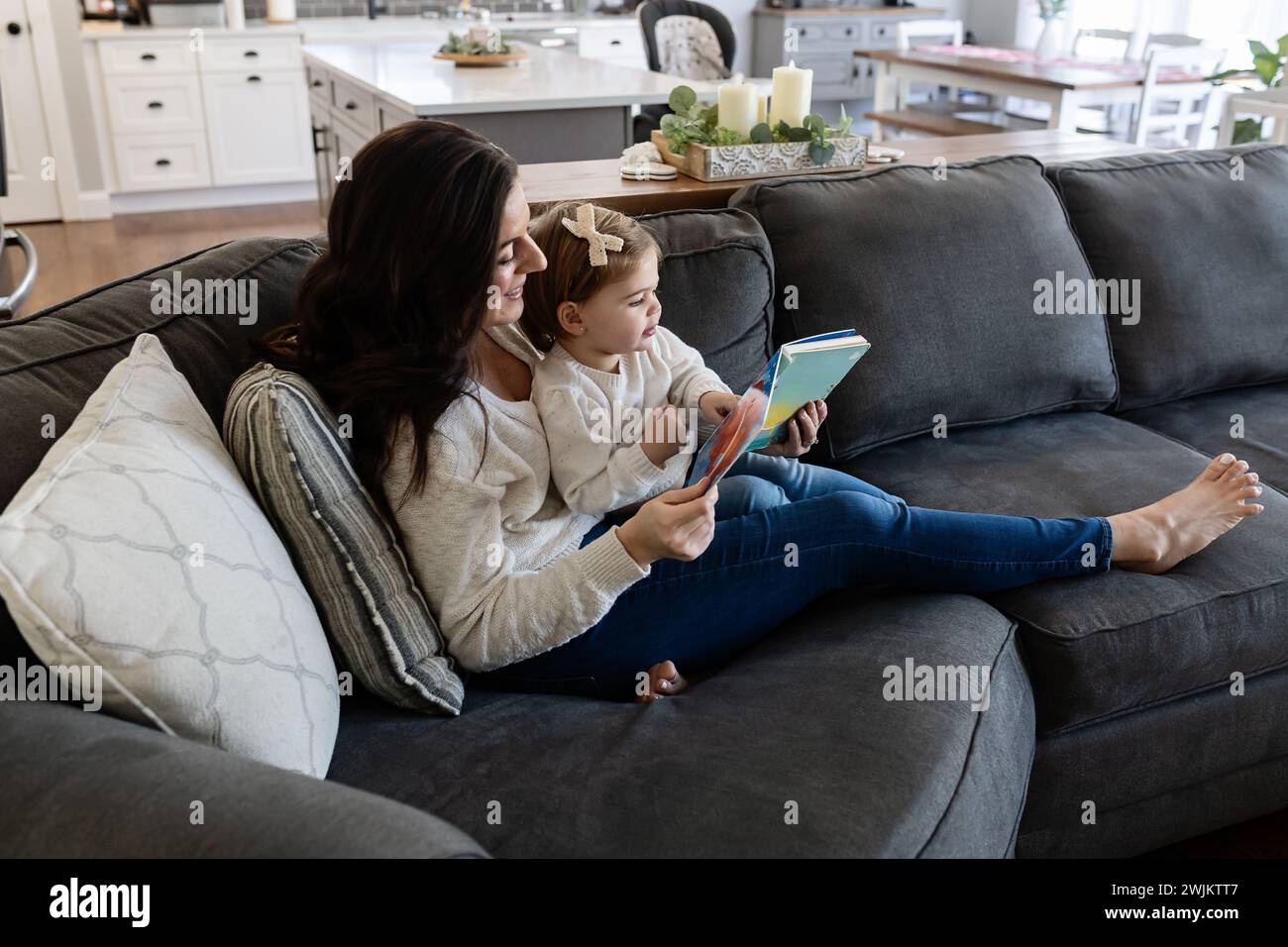 Maman et bébé lisant et Cuddling sur le canapé Banque D'Images