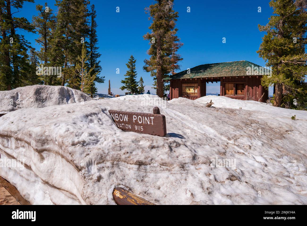 Panneau Rainbow point dans le parc national du canyon Bryce, couvert par une grande quantité de neige, journée chaude de printemps, ciel bleu clair. Cabane de repos à proximité. Grands arbres. Banque D'Images