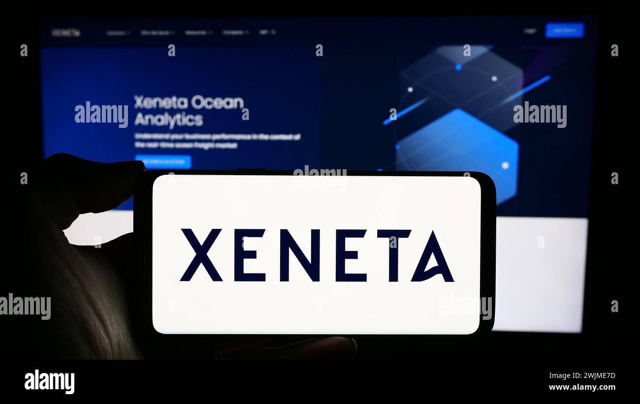 Personne tenant le téléphone portable avec le logo de la société norvégienne d'analyse d'expédition Xeneta COMME en face de la page Web d'affaires. Concentrez-vous sur l'affichage du téléphone. Banque D'Images