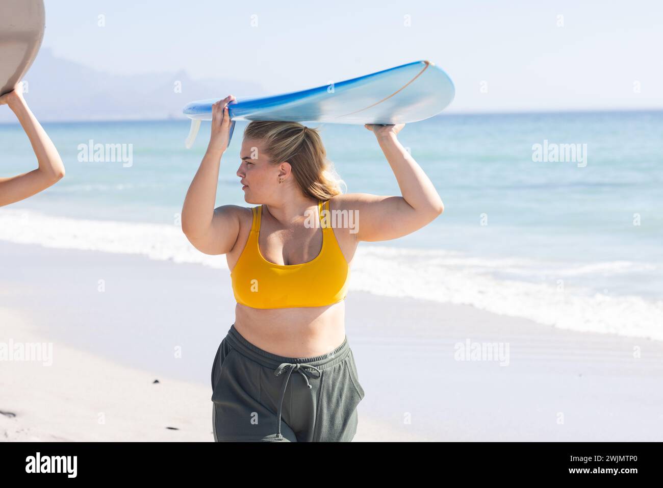 Une jeune femme caucasienne se prépare pour une séance de surf à la plage Banque D'Images