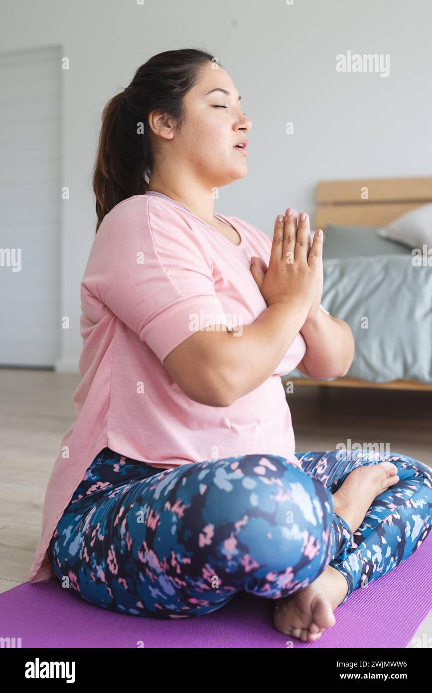 Jeune femme biraciale de grande taille pratique le yoga à la maison Banque D'Images