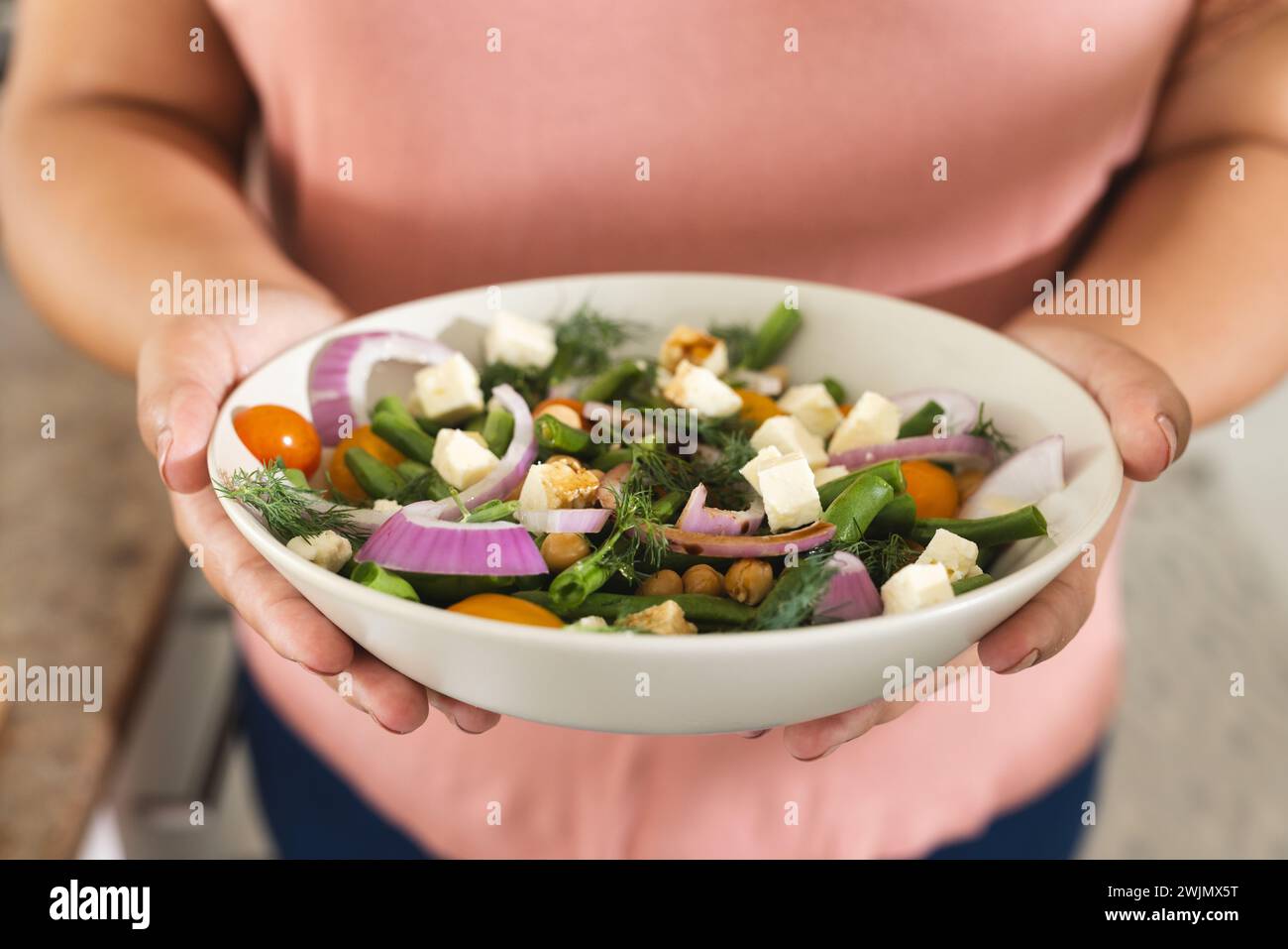 Femme présente une salade fraîche à la maison, avec un espace de copie Banque D'Images