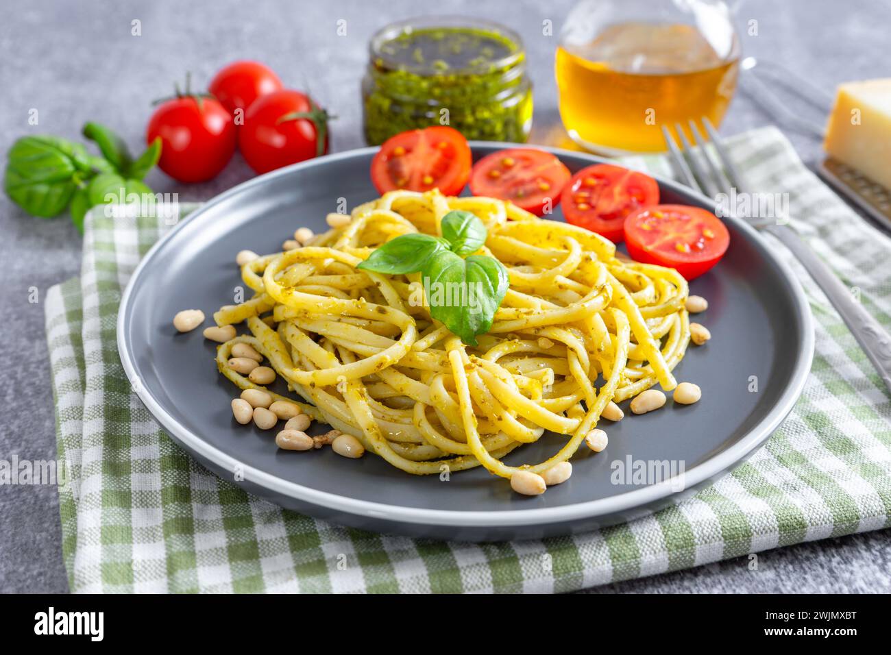 Pesto de pâtes, spaghetti à la sauce pesto et feuilles de basilic frais dans un bol noir sur fond de béton gris servi avec des ingrédients alimentaires. ita traditionnel Banque D'Images