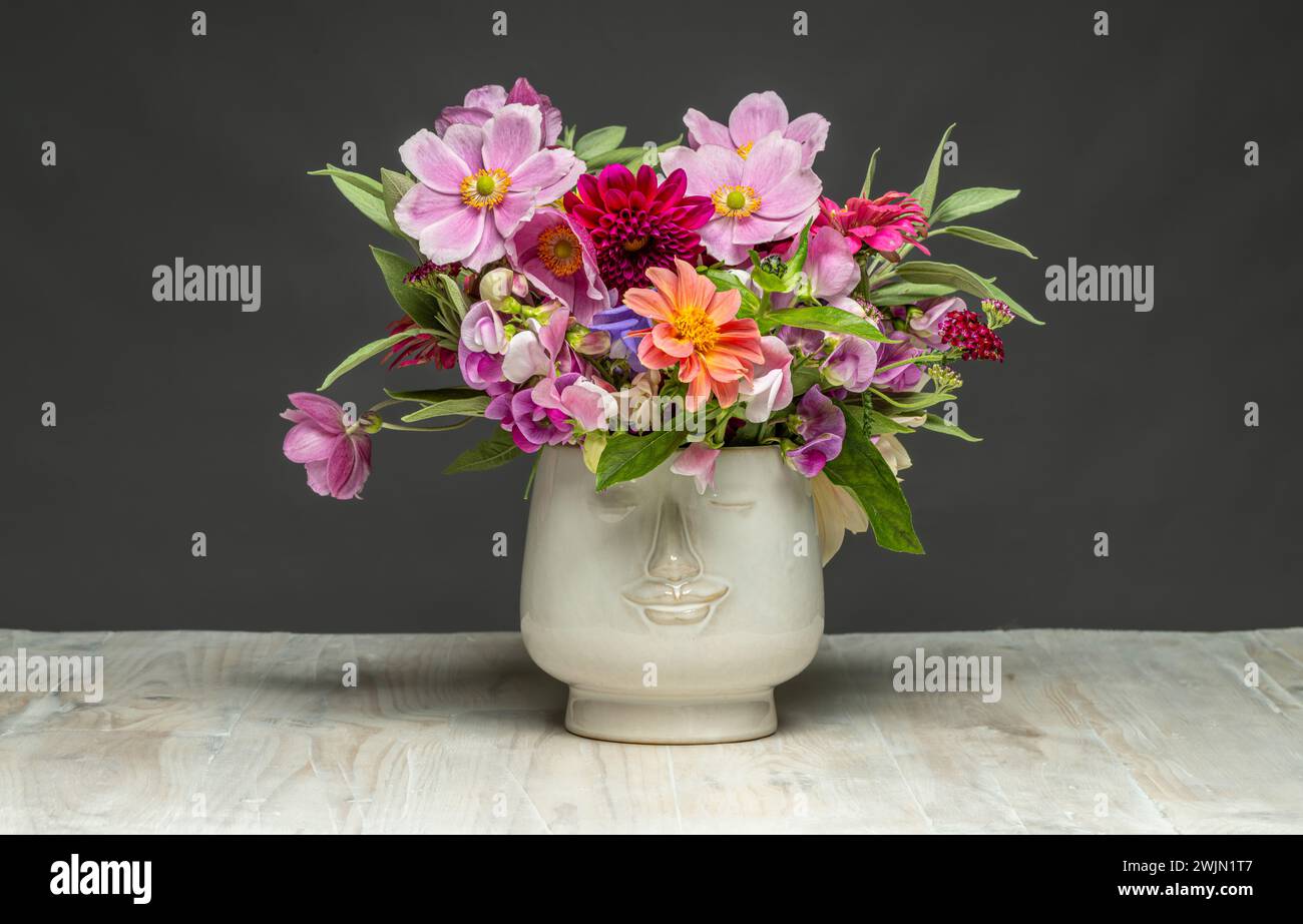 Fleurs coupées dans un vase visage en céramique blanche. Banque D'Images