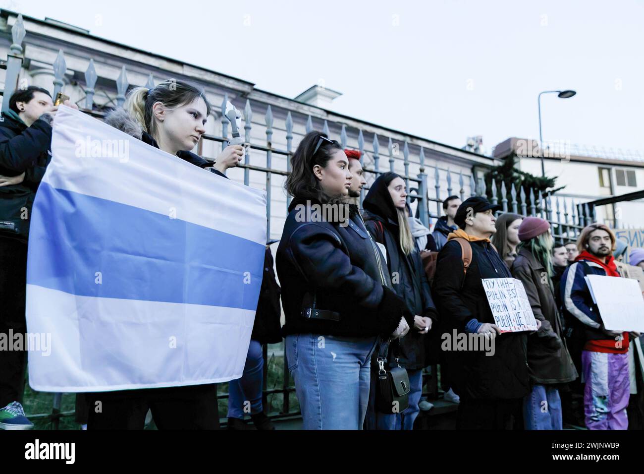 Une femme tient un drapeau blanc-bleu-blanc, qui est considéré comme un symbole du mouvement démocratique en Russie, participe à un rassemblement devant le bâtiment de l'ambassade russe à Varsovie après la nouvelle que l'homme politique Alexei Navalny est mort en prison. L'administration du Service pénitentiaire fédéral de l'Okrug autonome Yamalo-Nenets de la Fédération de Russie a signalé que l'homme politique Alexei Navalny était mort en prison. Il avait 47 ans. La cause de sa mort fait l'objet d'une enquête. Navalny avait été condamné à 19 ans de prison. Pendant sa détention, à partir de février 2021 Banque D'Images