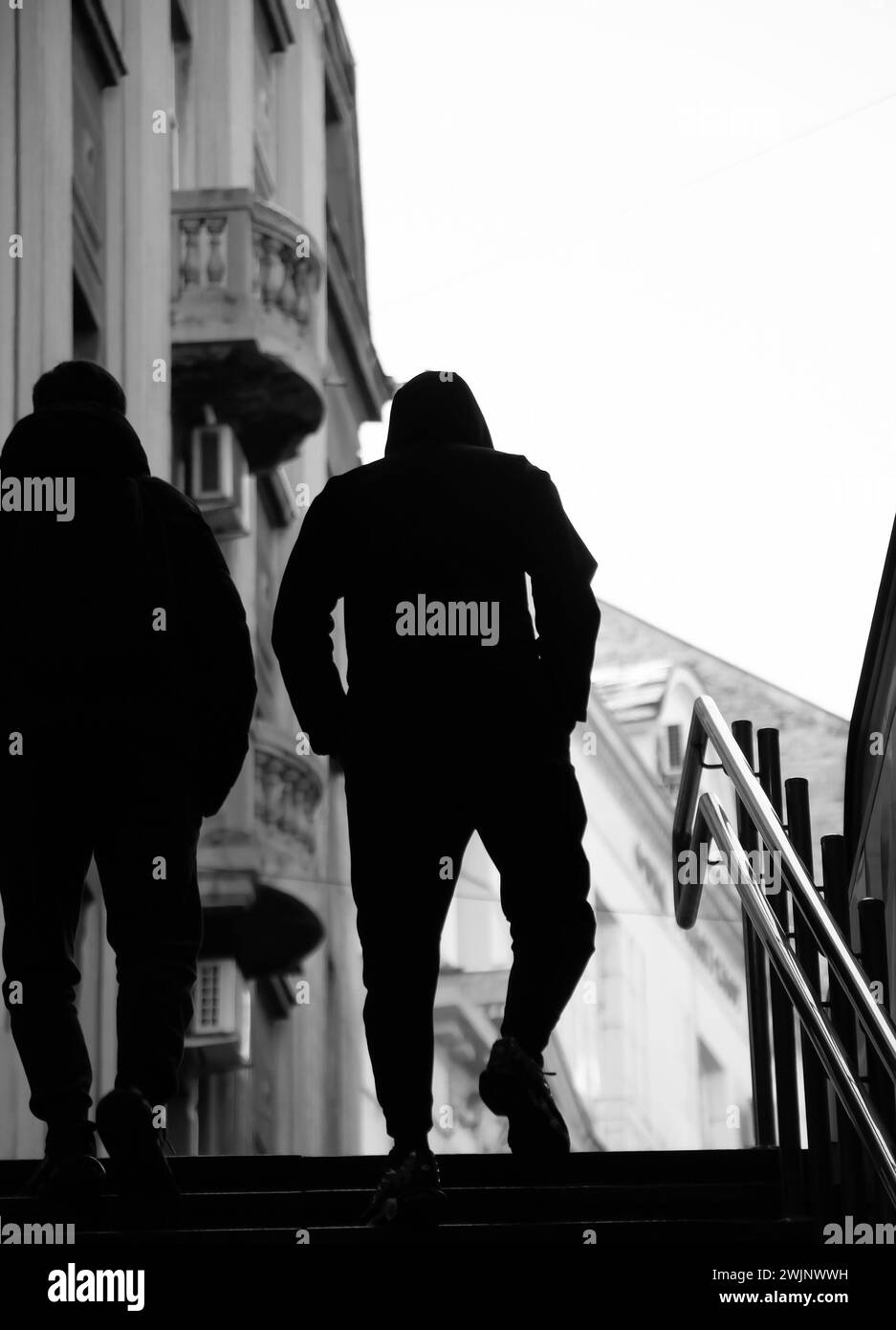 Silhouette de deux jeunes hommes avec les mains dans les poches marchant vers le haut des escaliers du métro de la ville, vue d'angle bas Banque D'Images