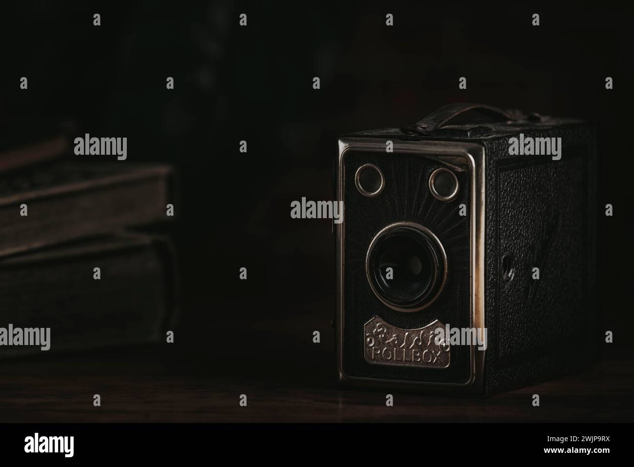 Vieille caméra de boîte sur un fond sombre à côté de vieux livres Banque D'Images