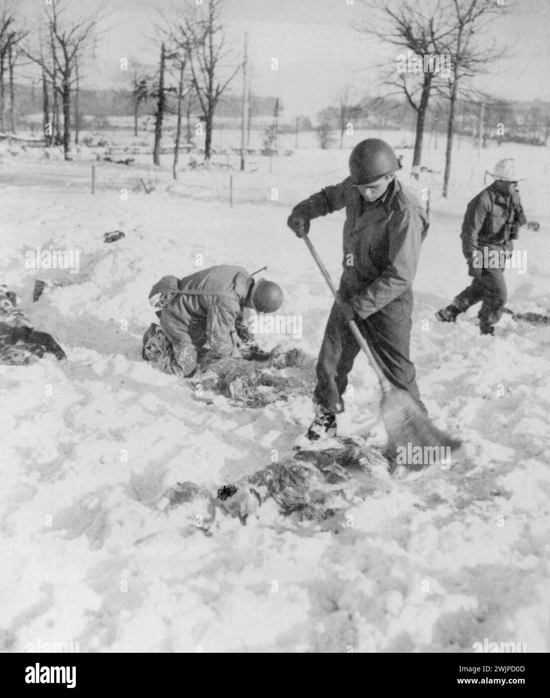 Récupérer les corps de camarades massacrés -- tâche désagréable de ces soldats américains récupérer les corps de leurs camarades qui ont été massacrés par les Allemands après avoir été faits prisonniers dans la récente route nazie à travers la Belgique. Dans ce champ, à la périphérie du village de Baugnez, un Yank balaie la neige d’un corps. 22 janvier 1945. (Photo d'Associated Press photo). Banque D'Images