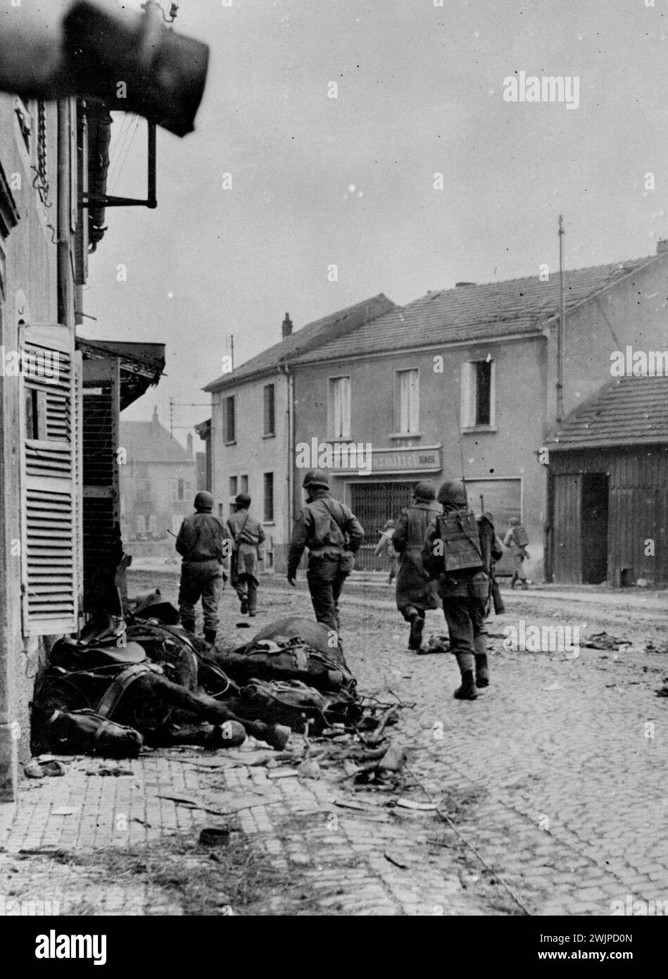 Les G.I d'une division d'infanterie américaine se dirigent vers le centre de la ville devant des chevaux de selle morts pendant les combats pour Metz. 22 janvier 1945. (Photo de la photographie officielle des États-Unis). Banque D'Images