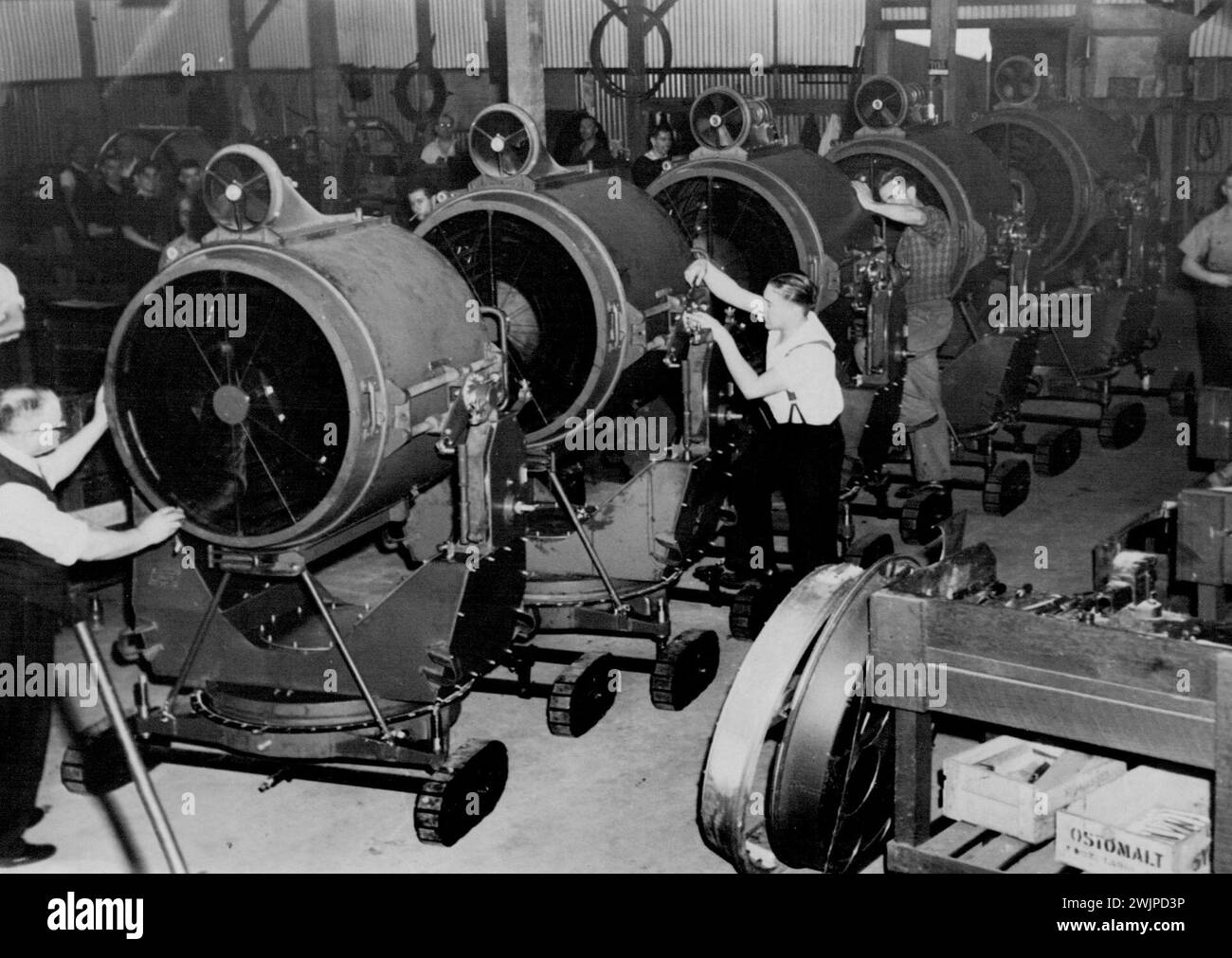 Lignes de blocage -- phares de recherche fabriqués en Australie. L'usine qui produit ces projecteurs a été « outillée » et a été en production dans un tiers du temps qu'il a fallu à une usine anglaise pour faire la même opération. Des projecteurs de fabrication australienne ont été fournis outre-mer aux forces alliées. Phares de tête sur la ligne de production. 30 avril 1947. Banque D'Images
