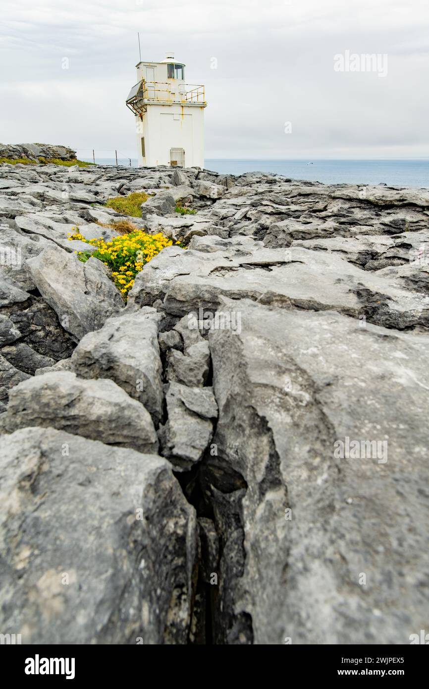 Black Head Lighthouse, situé dans le paysage rocheux rugueux de Burren, au milieu d'un paysage bizarre de montagnes calcaires escarpées et de côtes rocheuses, cou Banque D'Images