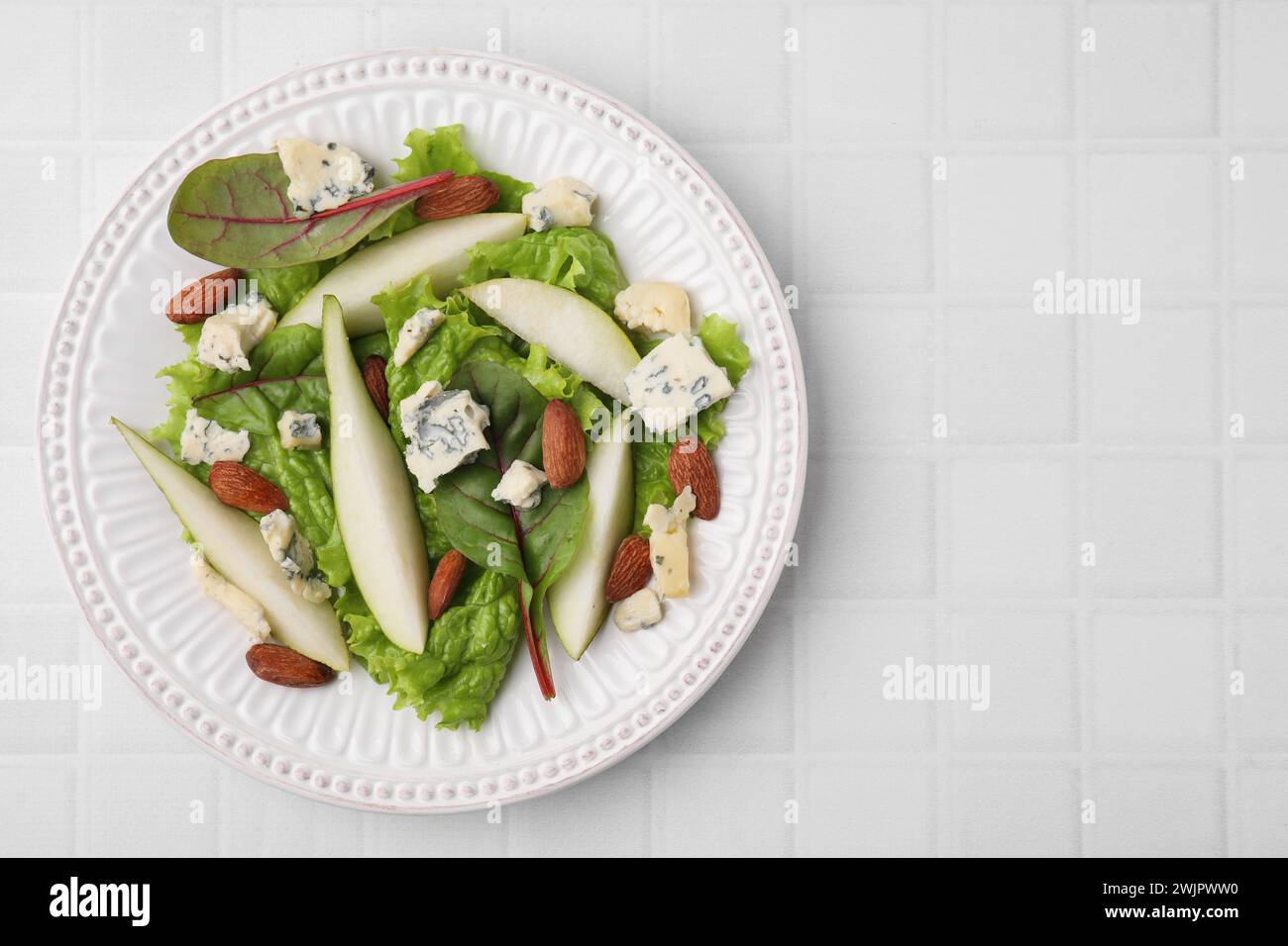 Délicieuse salade de poires sur table carrelée blanche, vue de dessus. Espace pour le texte Banque D'Images