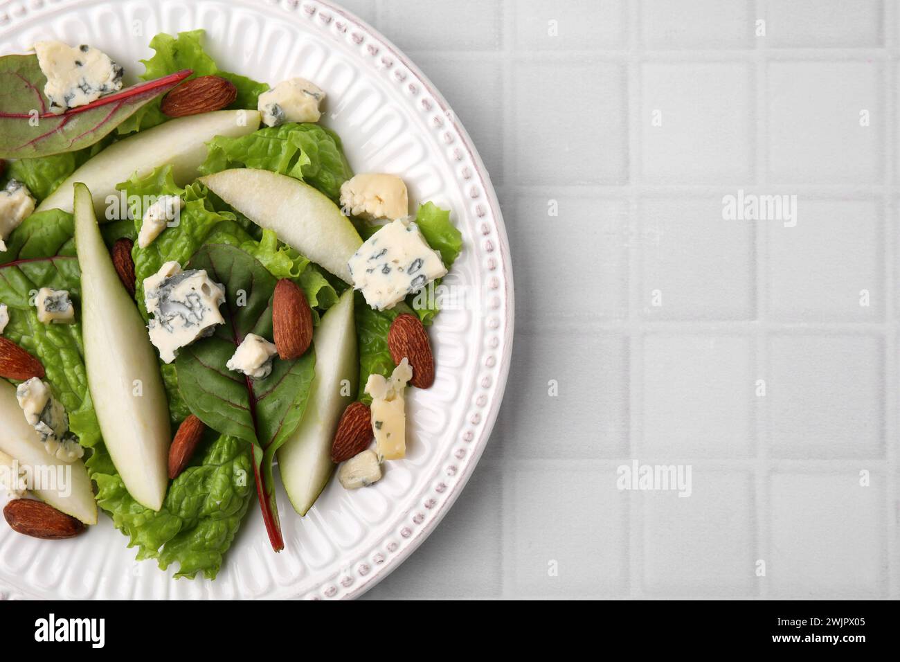 Délicieuse salade de poires sur table carrelée blanche, vue de dessus. Espace pour le texte Banque D'Images