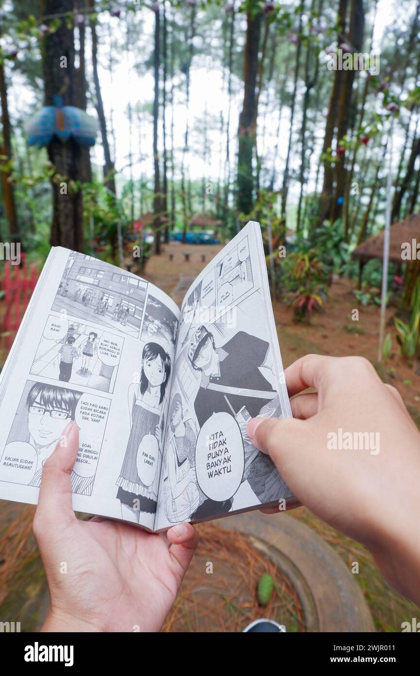 Photo d'une femme asiatique lisant une bande dessinée en indonésien Banque D'Images